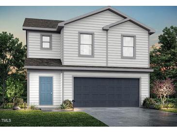 Two-story home with white siding, a blue front door, and a gray garage door, complemented by lush landscaping at 147 Landon Pl, Roxboro, NC 27573