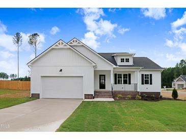 Charming, new construction one-story home with white siding, black accents, and a well-manicured front yard at 203 Sourgum Ct, Zebulon, NC 27597
