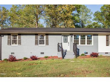 Charming home featuring a well-kept lawn and gray painted brick exterior, creating a welcoming curb appeal at 305 Gillis Rd, Roxboro, NC 27574