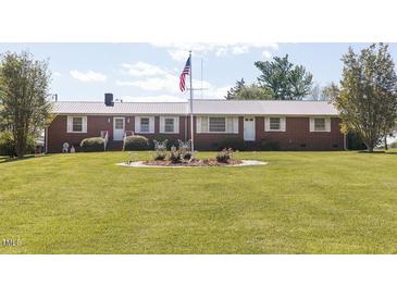 Charming brick ranch with manicured lawn, American flag, and butterfly garden at 481 Firetower Rd, Louisburg, NC 27549