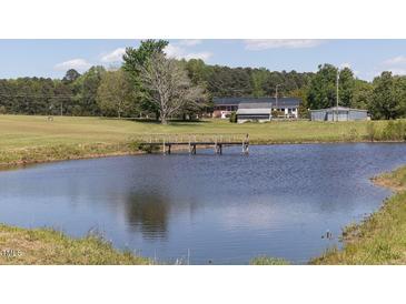 Scenic view of a tranquil pond with a wooden bridge leading to a charming country home in the background at 481 Firetower Rd, Louisburg, NC 27549