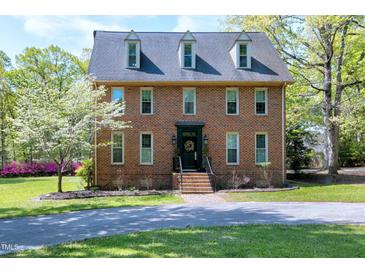 Charming brick home with a well-manicured lawn, dormer windows, and a welcoming front entrance at 8120 Stillbreeze Dr, Fuquay Varina, NC 27526