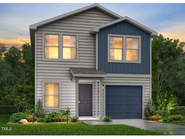 Charming two-story home featuring mixed siding and a two-car garage, surrounded by lush landscaping and trees at 99 Landon Pl, Roxboro, NC 27573