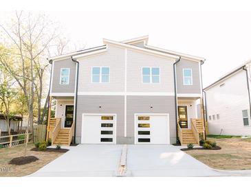Modern townhomes featuring a light gray exterior with white garage doors and wood stairs at 109 S Plum St, Durham, NC 27703