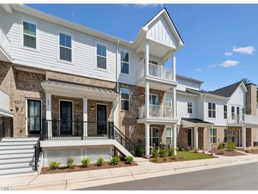 A beautiful exterior view of a modern brick and white townhouse with a cozy porch and balcony at 11549 Helmond Way # 103, Raleigh, NC 27617