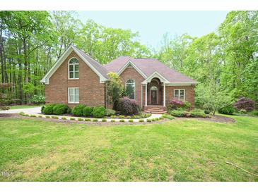 Charming brick home with lush landscaping and mature trees providing curb appeal and privacy at 14 Whit Ct, Angier, NC 27501
