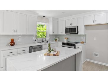 Bright kitchen features white cabinets, modern appliances, light countertops and a large window at 1514 Goodwin Rd, Durham, NC 27712