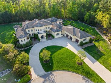 Stunning aerial view of an estate home with circular driveway, lush landscaping, and attached garages at 16 Portofino Pl, Durham, NC 27707