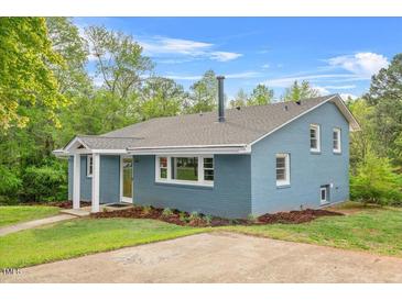 Charming two-story home with a brick exterior and landscaped yard showcasing a well-maintained lawn and colorful foliage at 1751 Riverside Dr, Hillsborough, NC 27278