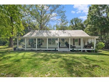 Charming single story home with a sprawling front porch, metal roof and mature trees at 1835 Pearidge Rd, Angier, NC 27501