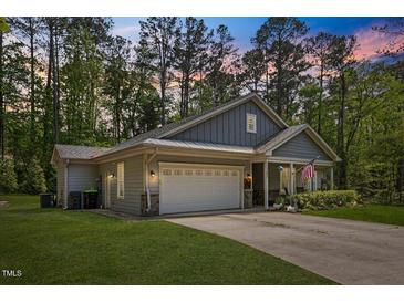 Charming one-story home with a two-car garage, manicured lawn, and inviting front porch at 205 Sacred Fire Rd, Louisburg, NC 27549