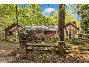 Charming brick home surrounded by lush greenery and a rustic wooden fence creating curb appeal at 480 Big Branch Dr, Pittsboro, NC 27312