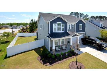 Charming two-story home featuring a welcoming front porch and well-manicured lawn, enclosed by a white fence at 490 Mallard Loop Dr Dr, Clayton, NC 27527