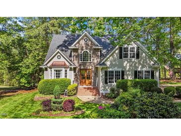 Charming stone front home with mature landscaping, manicured lawn, and arched window at 5113 Windance Pl, Holly Springs, NC 27540