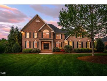 Elegant brick home boasting a manicured lawn, mature trees, and classic black shutters at 10 Twinleaf Pl, Durham, NC 27705
