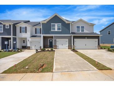 New townhomes feature modern exteriors with attached garages and freshly laid sod at 1048 Winding Spring Dr, Mebane, NC 27302