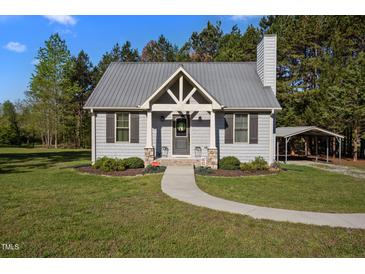Charming one-story home with a metal roof, gray siding, and a welcoming walkway, plus covered parking on a lush, green lot at 108 Ruff Davis Rd, Roxboro, NC 27574