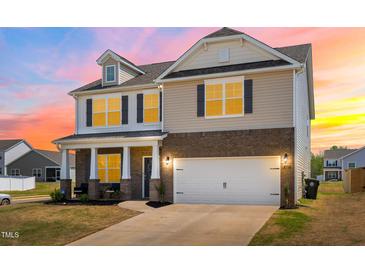 Beautiful two-story home with brick and vinyl siding and an attached two-car garage, and front porch at 1427 Carisbrooke Dr, Mebane, NC 27302