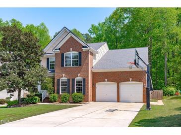Charming two-story brick home with a two-car garage, well-manicured lawn, and a basketball hoop at 2412 Castleburg Dr, Apex, NC 27523