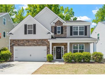 Charming two-story home with stone and siding exterior, two-car garage, and well-manicured landscaping at 3411 Massey Pond Trl, Raleigh, NC 27616