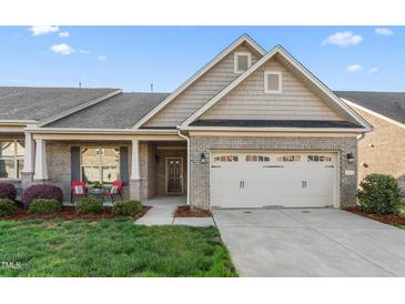 Charming brick home featuring a two-car garage and a cozy front porch seating area at 4020 Kinsley Trce, Burlington, NC 27215