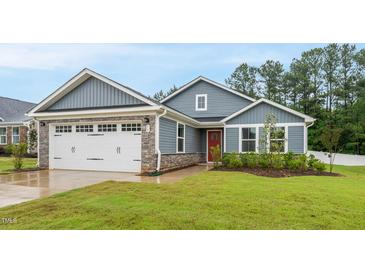 Charming single-story home with a well-manicured lawn, attached garage, and inviting red front door at 55 Boots Ridge Way, Franklinton, NC 27525