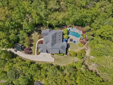 Stunning aerial view of the home with a pool, lush landscaping and surrounded by mature trees at 6824 Wood Forest Dr, Cary, NC 27519