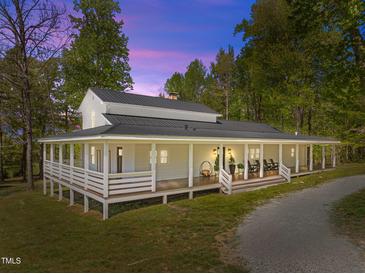 Stunning exterior of a home with a wraparound porch and a metal roof surrounded by mature trees at 9400 Wheelers Church E Rd, Hurdle Mills, NC 27541