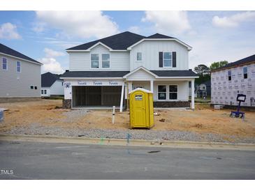 Two-story home featuring a black roof, light siding, and a welcoming front porch, still under construction in a new community at 1121 Landen Creek Ln, Zebulon, NC 27597
