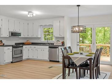 Bright kitchen features white cabinets, stainless steel appliances and a dining area with a door to the deck at 1209 Shincliffe Ct, Cary, NC 27511