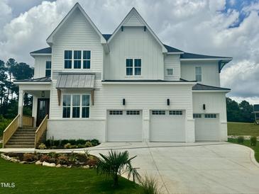 Attractive white home with a multi-car garage, lush landscaping, and a welcoming entrance with wooden accents at 1217 Azalea Garden Cir, Raleigh, NC 27603