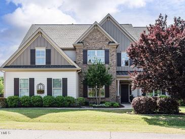 Charming two-story home featuring brick and siding exterior, manicured lawn, and mature landscaping at 212 Listening Ridge Ln, Cary, NC 27519