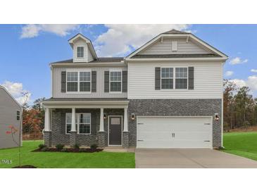 Two-story home featuring a two-car garage, brick facade, and a welcoming front porch with classic architectural style at 2739 Luxborough Ln, Mebane, NC 27302