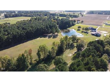 Expansive aerial view of property featuring a pond, barn, and surrounding fields and trees at 2747 Beasley, Benson, NC 27504