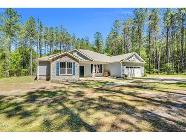 Charming single-story home with stone accents and an inviting front porch, surrounded by lush trees at 2784 Norrington Rd, Lillington, NC 27546