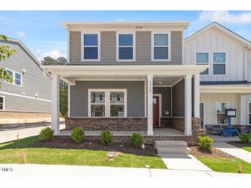 Charming two-story home featuring a welcoming front porch with stylish brick accents and manicured landscaping at 3715 Rosebush Dr, Zebulon, NC 27597