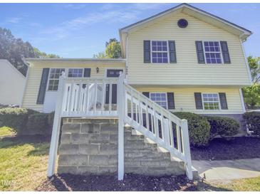 Charming two-story home with yellow siding, dark shutters, and a well-maintained landscaped yard at 5600 Brandycrest Dr, Raleigh, NC 27610