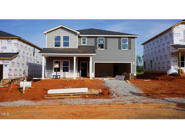 New two-story home with gray siding, an open garage, and a covered front porch under construction at 724 Deschutes Dr, Garner, NC 27529