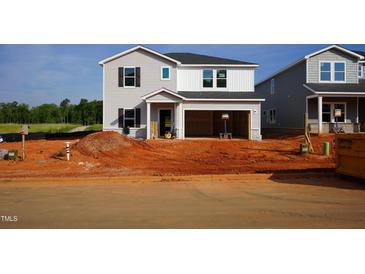 New construction home with a two-car garage and gray vinyl siding awaits its final touches at 728 Deschutes Dr, Garner, NC 27529