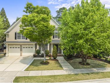Charming two-story home with a two car garage and landscaped front yard, including lush green trees at 909 Grogans Mill Dr, Cary, NC 27519