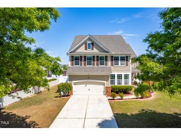 Two story home featuring well maintained lawn, two car garage, and shuttered windows at 112 Gadsbury Dr, Holly Springs, NC 27540