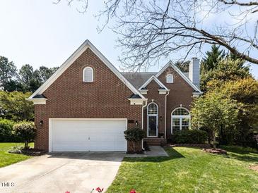 Charming brick home with a well-manicured lawn, two-car garage and mature tree in the front yard at 117 Whitehaven Ln, Cary, NC 27519