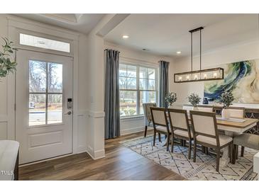 Elegant dining room with modern light fixture, stylish rug, and ample natural light from a large window at 125 Verona Villa Dr, Burlington, NC 27215