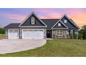 Charming home with a three-car garage, stone accents, and a well-manicured lawn at sunset at 194 Spring Hill Church Rd, Lillington, NC 27546