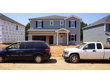 Two story home with attached garage and blue and gray siding under clear sky in developing neighborhood at 2227 Cherry Creek Rd, Haw River, NC 27258