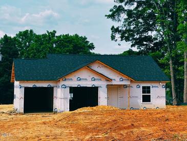New construction home featuring a two-car garage and dark roofing, surrounded by lush green trees at 2235 Melfield Dr, Haw River, NC 27258