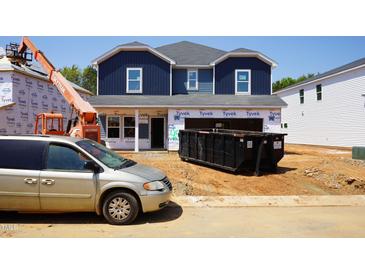 New construction home featuring a blue two-story facade and construction equipment on a sunny day at 2251 Cherry Creek Rd, Haw River, NC 27258