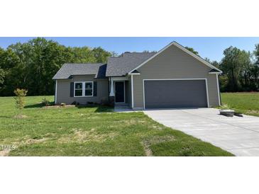 New construction home featuring a two-car garage, neutral siding, and a well-manicured lawn at 261 Phil Jack Rd, Dunn, NC 28334