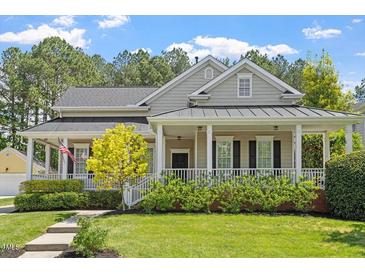 Charming home with a welcoming front porch, lush landscaping, and manicured lawn at 30038 Village Park Dr, Chapel Hill, NC 27517