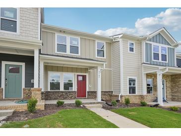 Charming townhome featuring brick accents, a red front door, and meticulously maintained landscaping at 3705 Rosebush Dr, Zebulon, NC 27597